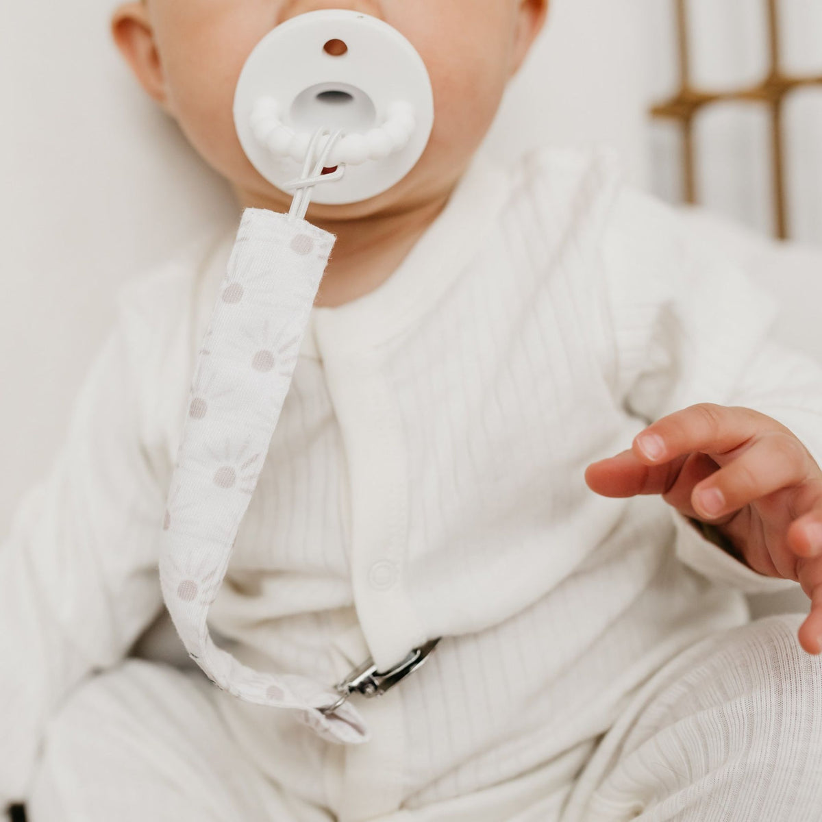 Baby sucks on pacifier attached to Copper Pearl Binky Clip Set - Bliss