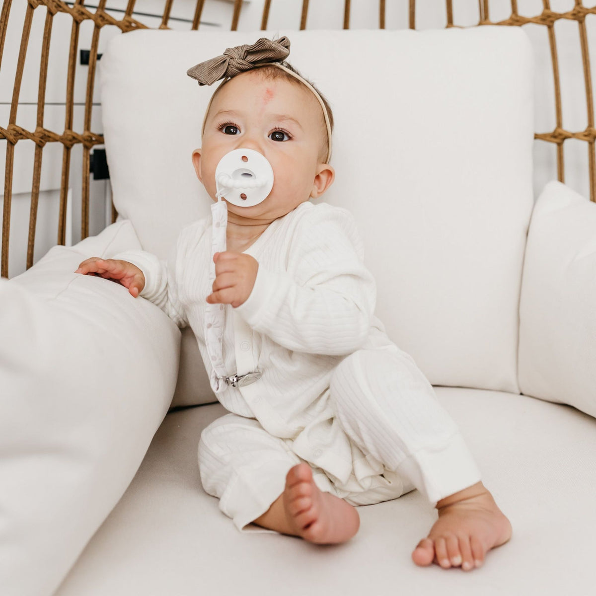 Baby sucks on pacifier attached to Copper Pearl Binky Clip Set - Bliss