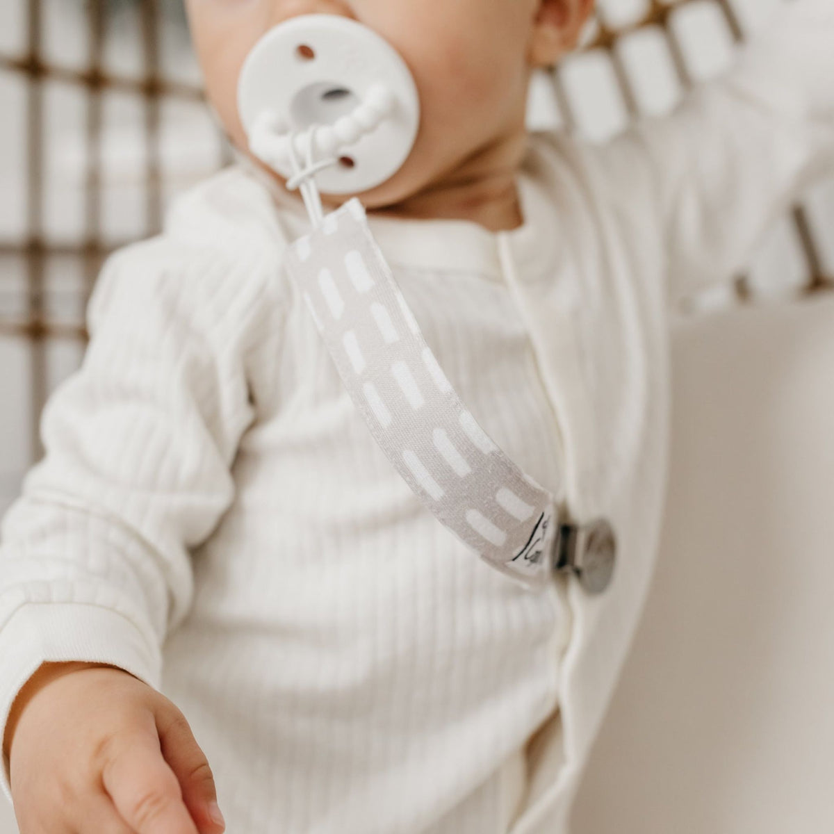 Baby sucks on pacifier attached to Copper Pearl Binky Clip Set - Bliss