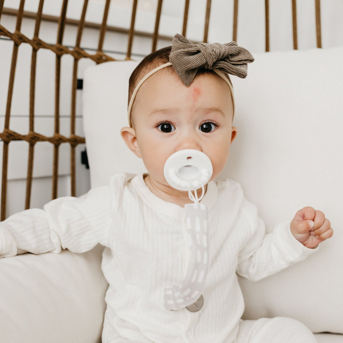 Baby sucks on pacifier attached to Copper Pearl Binky Clip Set - Bliss