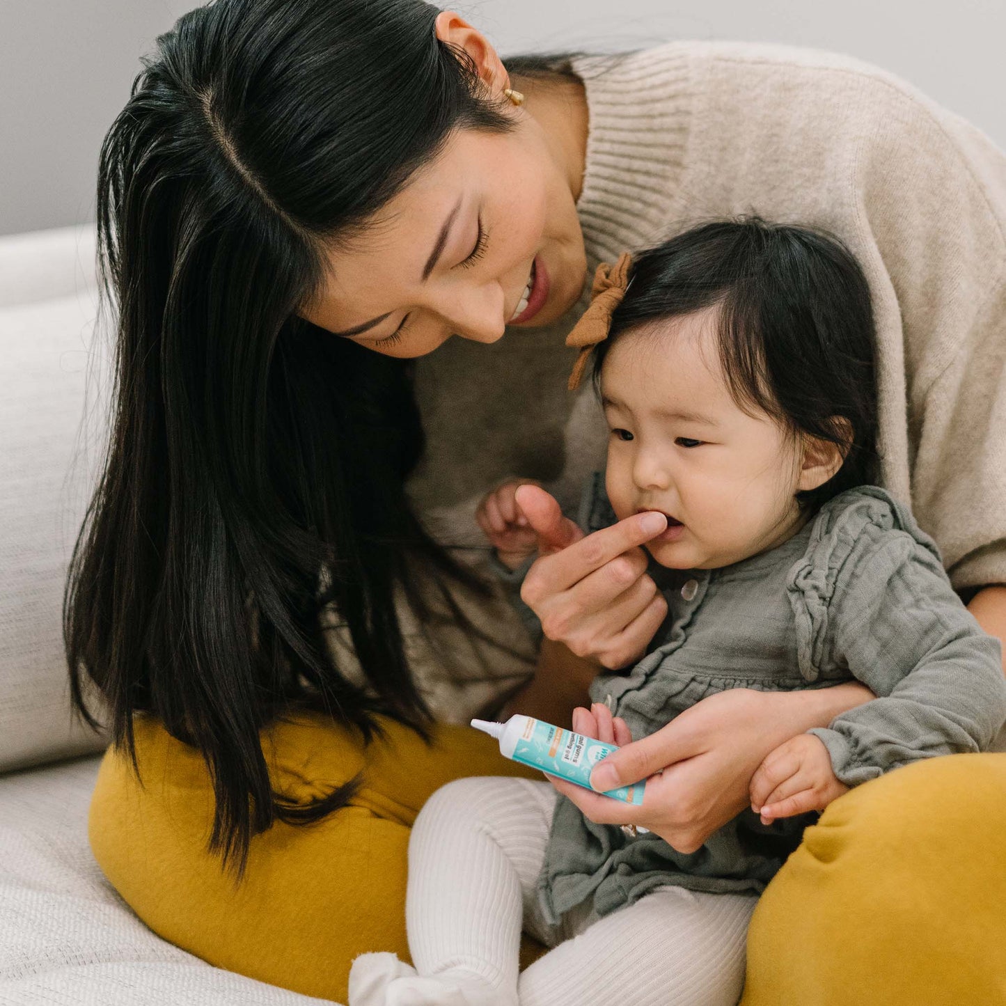 Mom using Wink Well Cool Gums Teething Gel on Baby