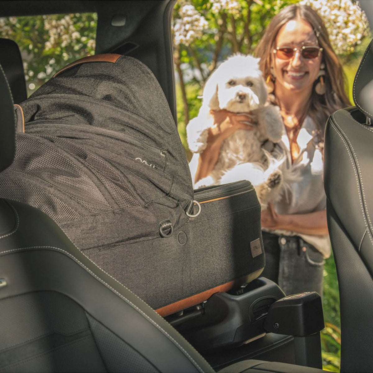 Woman placing dog in Tavo Maeve Pet Car Seat - Medium Flex - Onyx in vehicle