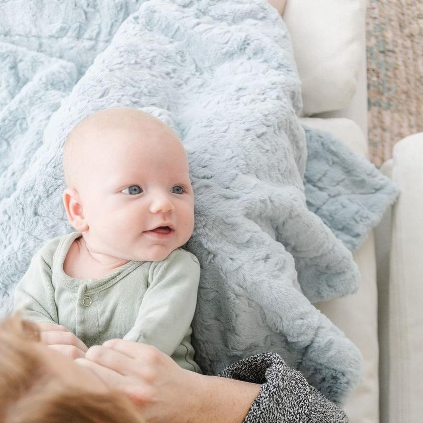 Baby laying on Saranoni Receiving Dream Blanket - Heather Blue