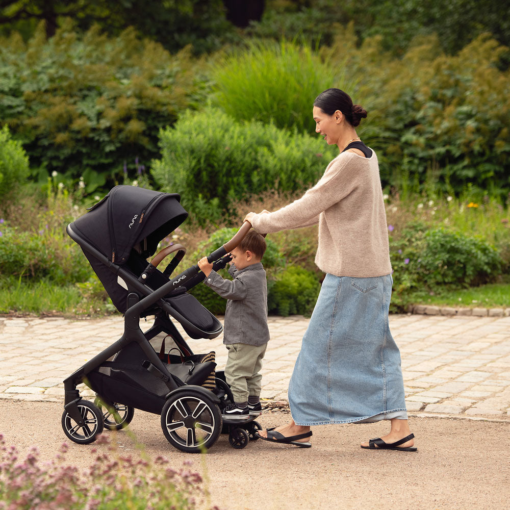 Mom pushes child on Nuna DEMI Next Stroller with Rider Board