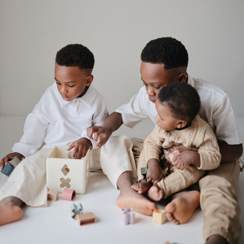 Kids playing with Mushie Shape Sorting Box