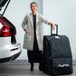 Woman standing next to car with Nuna Wheeled Travel Bag - Indigo